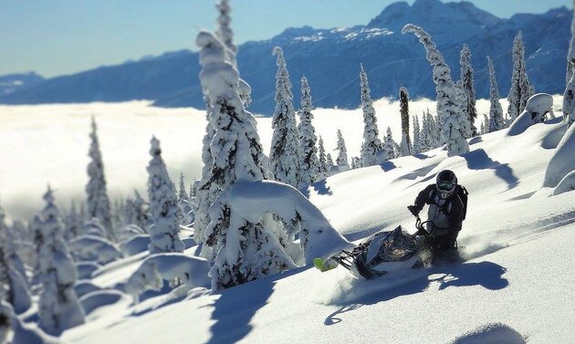 A rider in powder on Frisby Ridge above a valley full of cloud