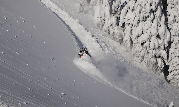 A rider cutting across a steep powder slope near Sicamous
